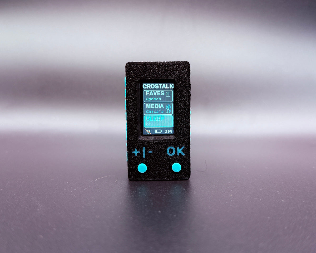 CROSTALK front view: black textured case, color screen showing the Faves, Media and Sleep menu, and two teal buttons