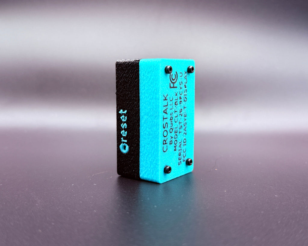 CROSTALK rear three-quarter view showing the teal bottom shell with product label and the recessed reset button on the side