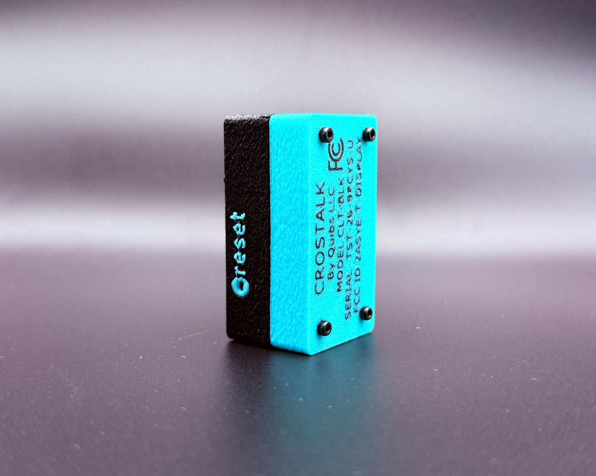 CROSTALK rear three-quarter view showing the teal bottom shell with product label and the recessed reset button on the side